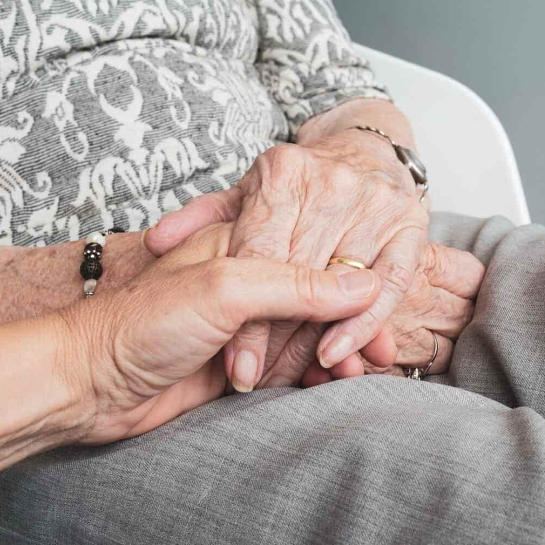 la mano de una mujer sostiene la mano de una mujer mayor, en señal de apoyo