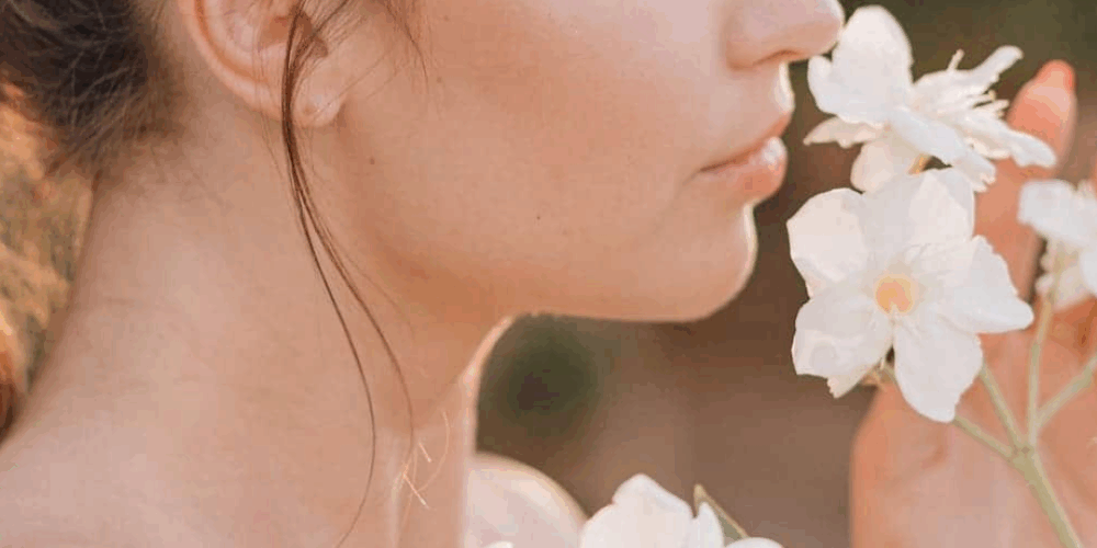 una mujer oliendo unas flores