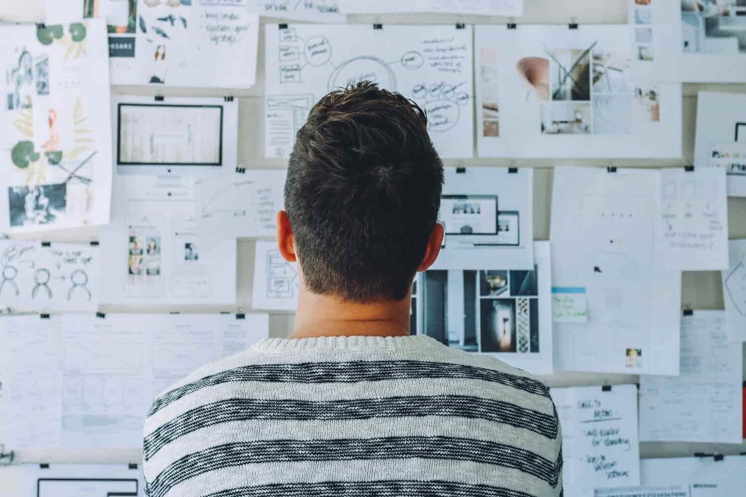 un hombre viendo una pared llena de documentos e imágenes