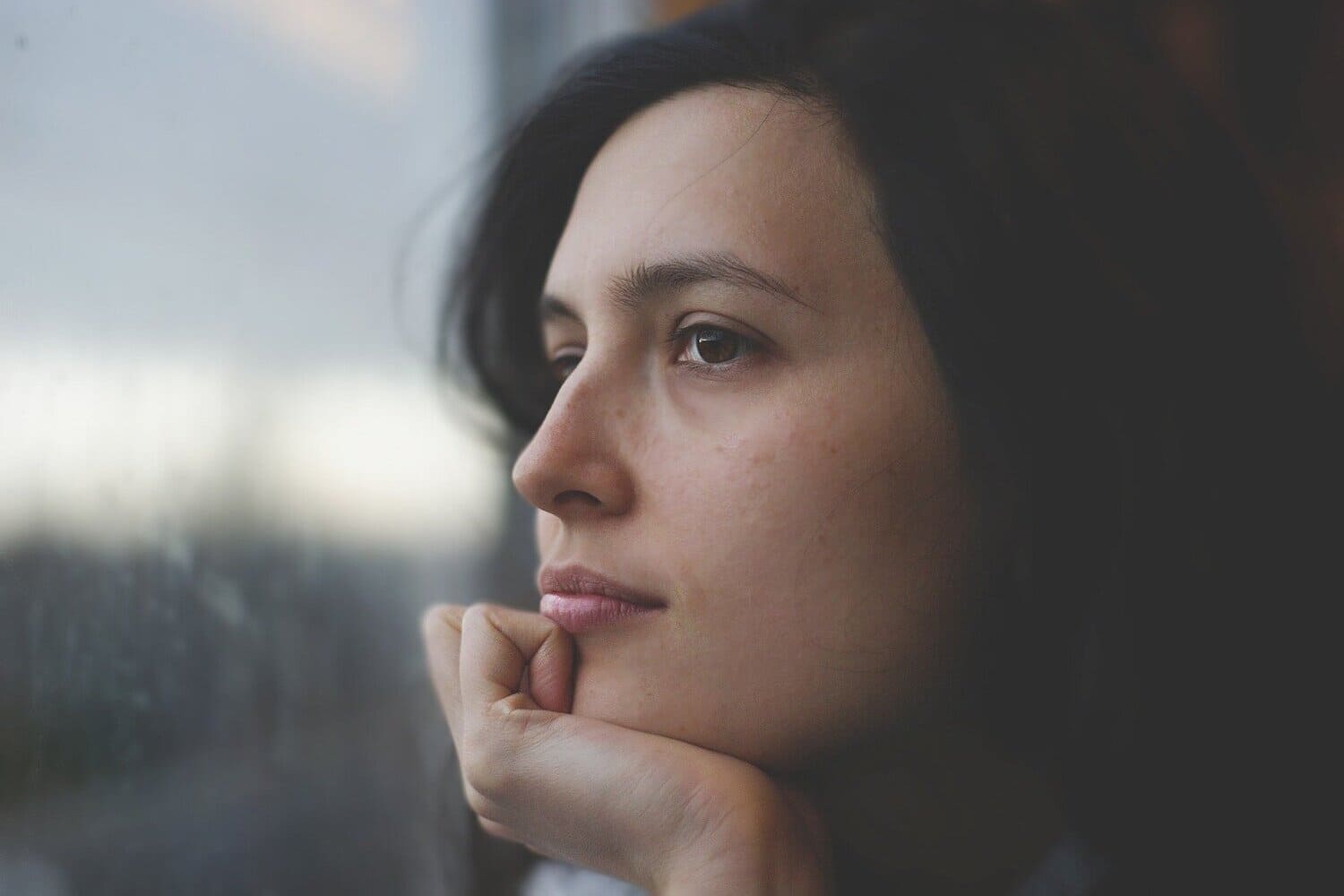 una mujer viendo por una ventana hacia el exterior