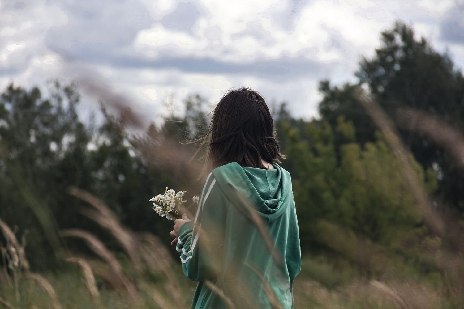 una mujer en medio de un campo, sosteniendo unas flores