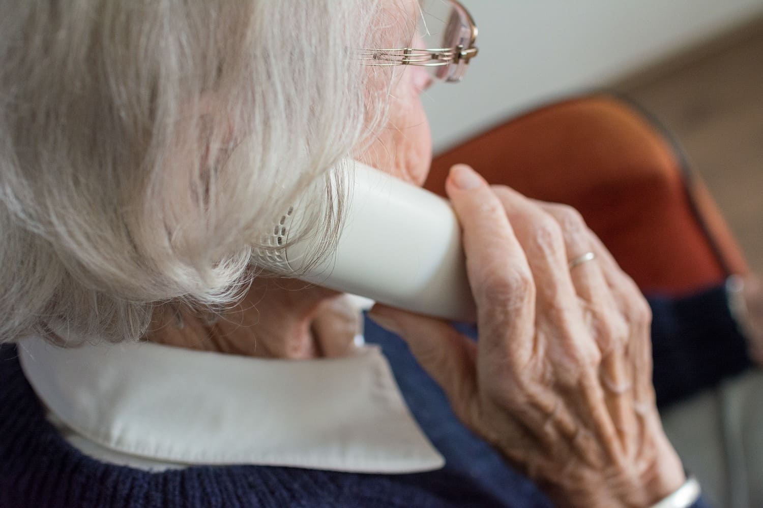 una mujer mayor sostiene un teléfono al lado de su oreja