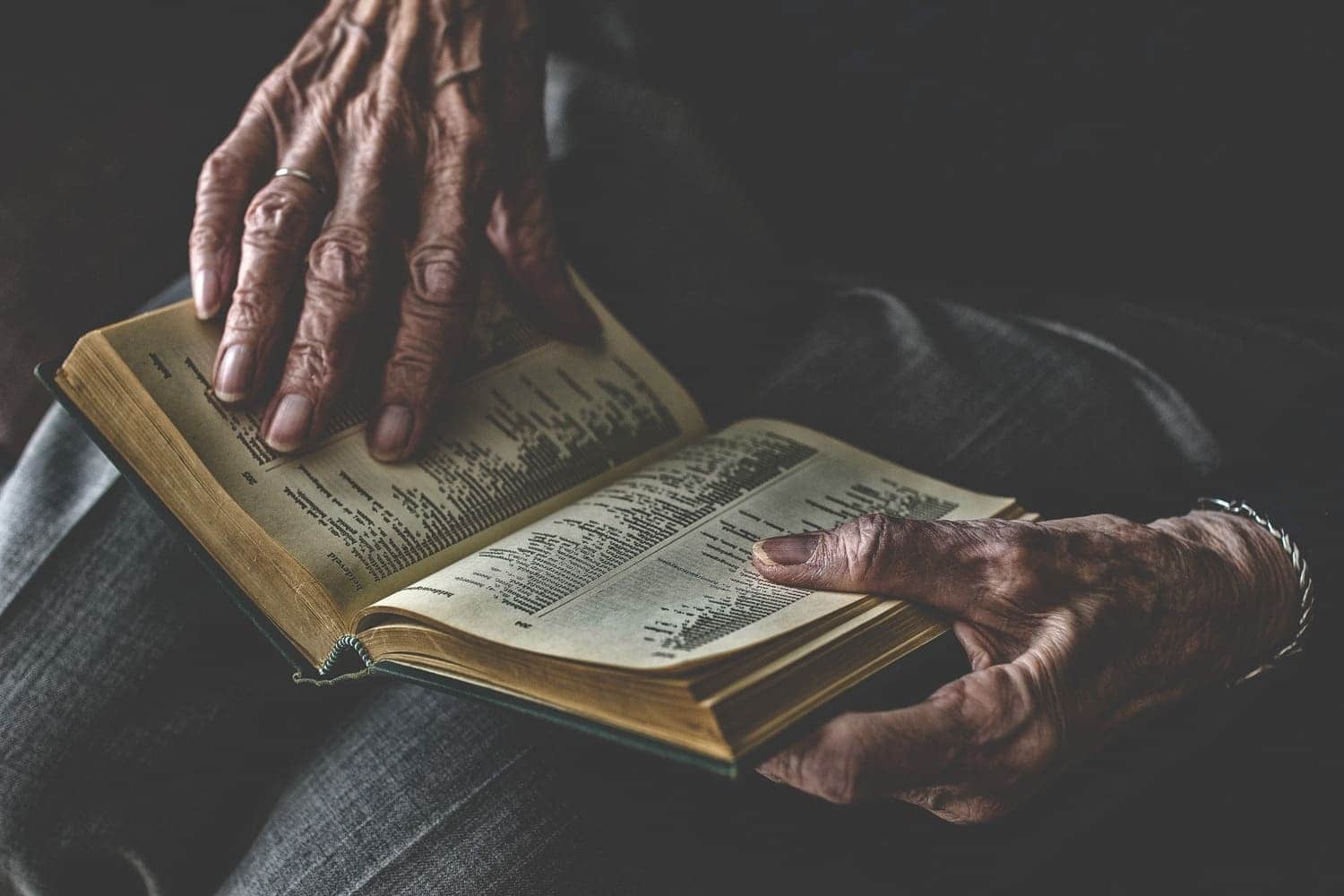 las manos de una señora mayor sostienen un libro abierto