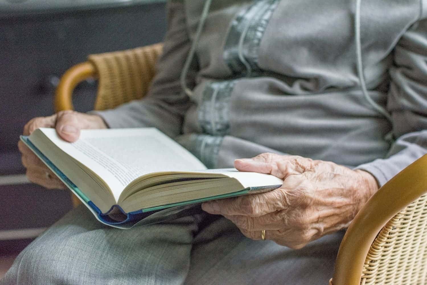 una persona mayor sostiene un libro que aparentemente lo está leyendo