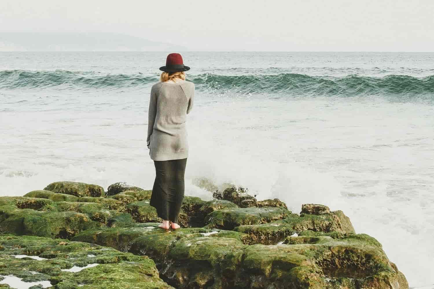 una mujer sobre unas rocas a la orilla del mar