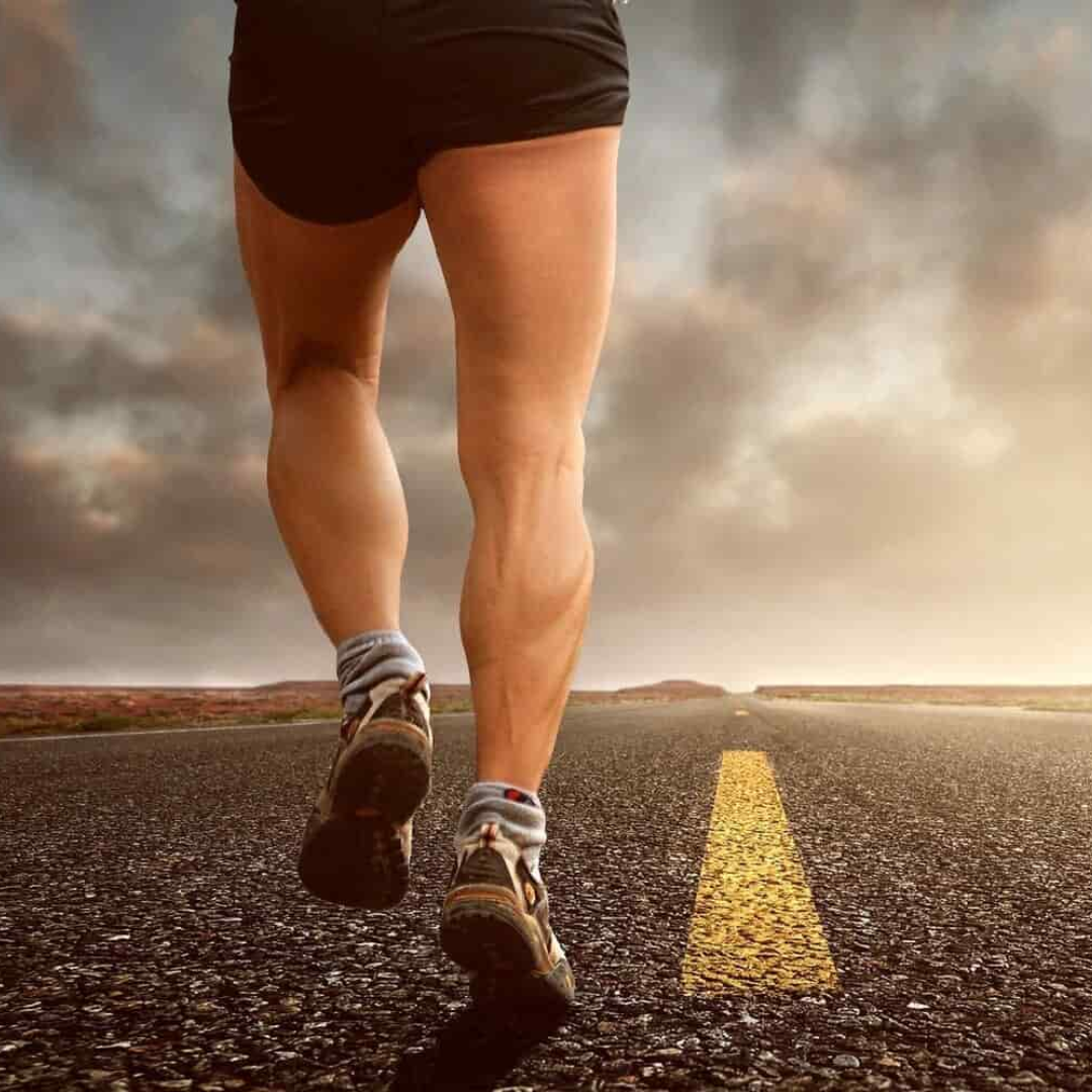 imagen de las piernas de un hombre que va corriendo por una carretera no transitada