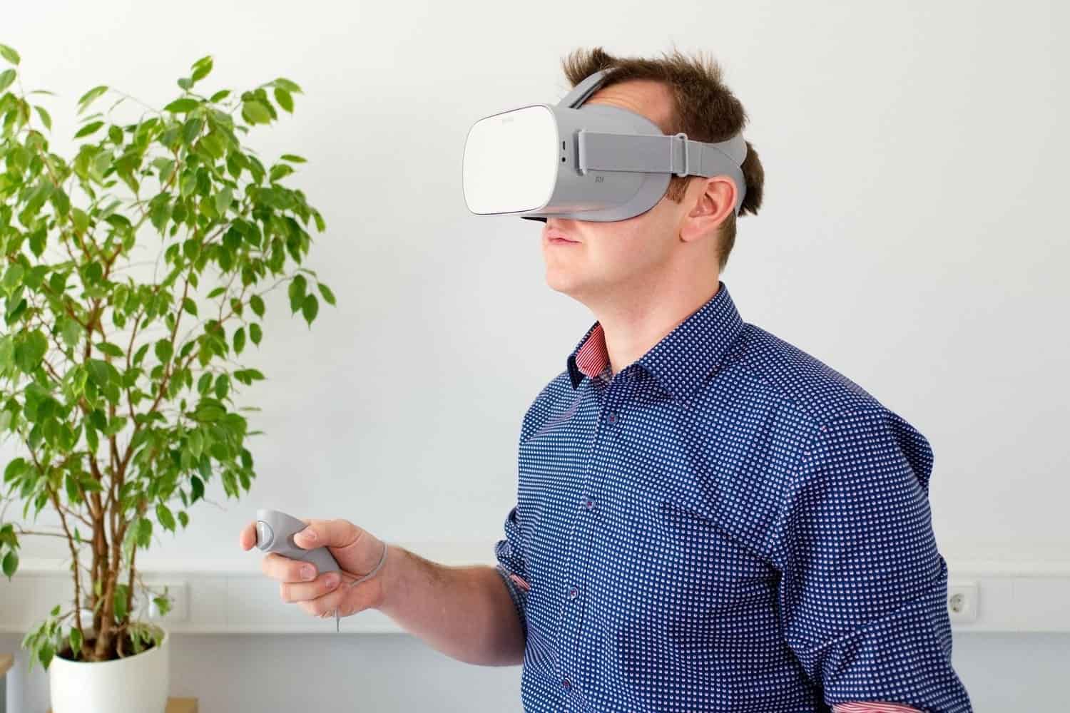 un hombre que lleva gafas de Realidad Virtual mientras sostiene en su mano derecha el mando de estas