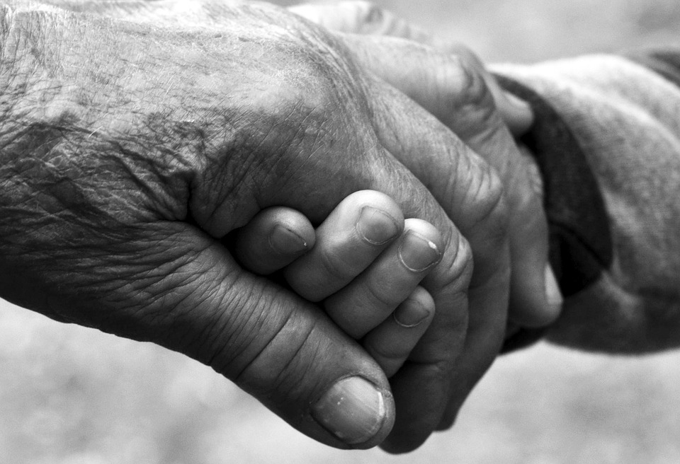 dos manos sosteniéndose la una a la otra, una d ellas es una persona mayor y la otra es la de un niño o joven