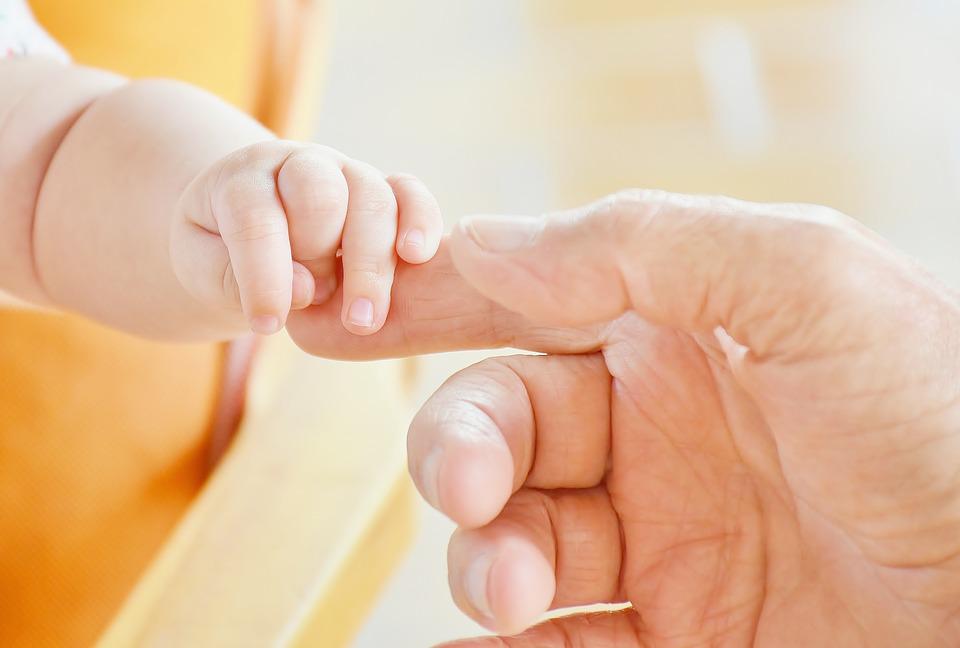 la mano de un bebé sostiene un dedo de la mano derecha de una persona mayor
