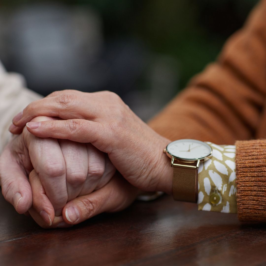 una persona sostiene la mano de un adulto mayo queriendo trasmitirle su apoyo; es una de las acciones a tener en cuenta al momento de tratar con una persona que padece de Parkinson