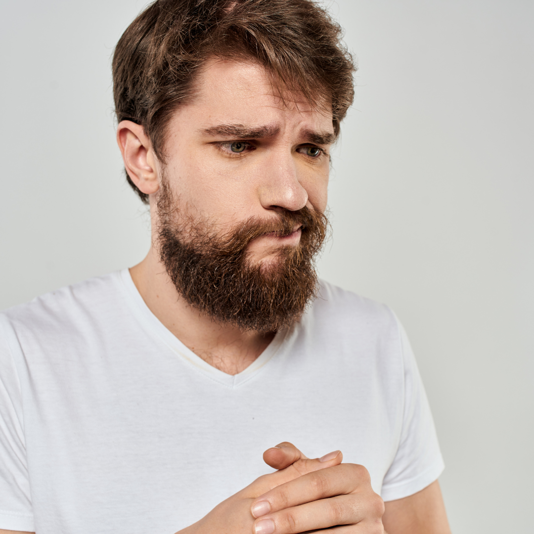 hombre joven que sostiene entrelazadas sus manos a la altura del pecho mientras la expresión de su cara (mueca con la boca hacia el lado izquierdo) parece ser de preocupación o de no saber muy bien que es lo que hace o está pasando . La imagen hace referencia a las dificultades que trae la aprosodia