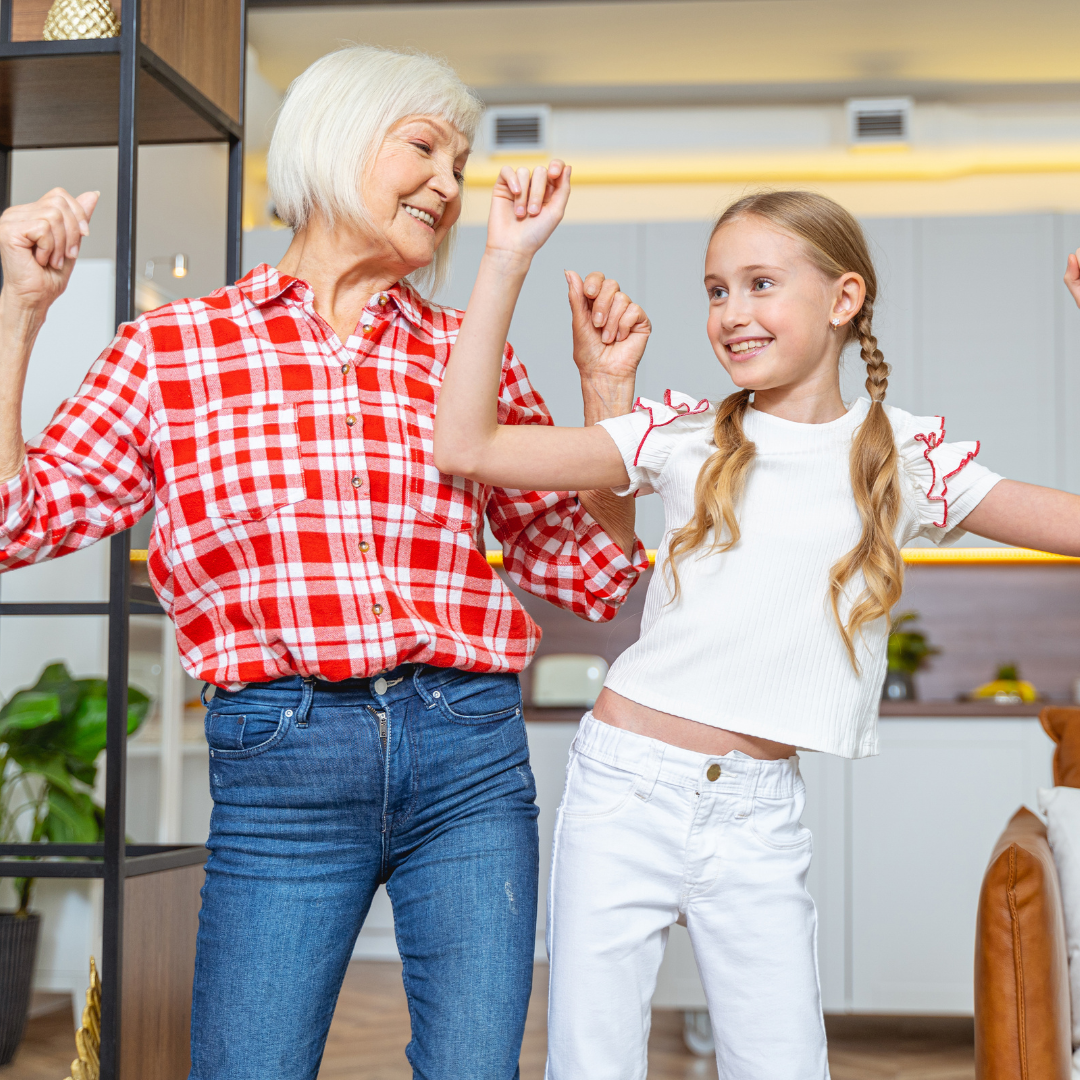 una señora y una niña bailan mientras sonríen ampliamente, esta imagen hace referencia a la relación que existe entre el baile y la salud