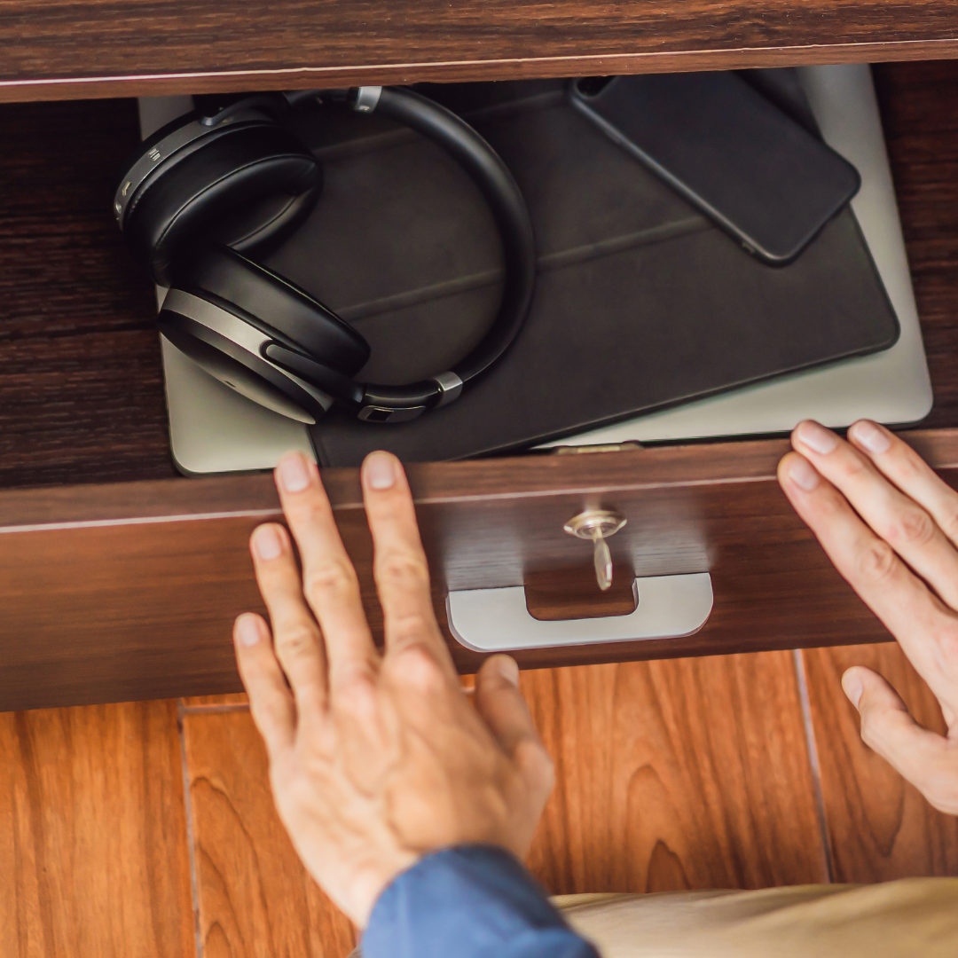 en un cajón se hace ademan de guardar bajo llave, aparatos tecnológicos, tales como una tablet, un móvil, un ordenador y unos auriculares . Imagen que hace referencia a "Desconectar para Reconectar"